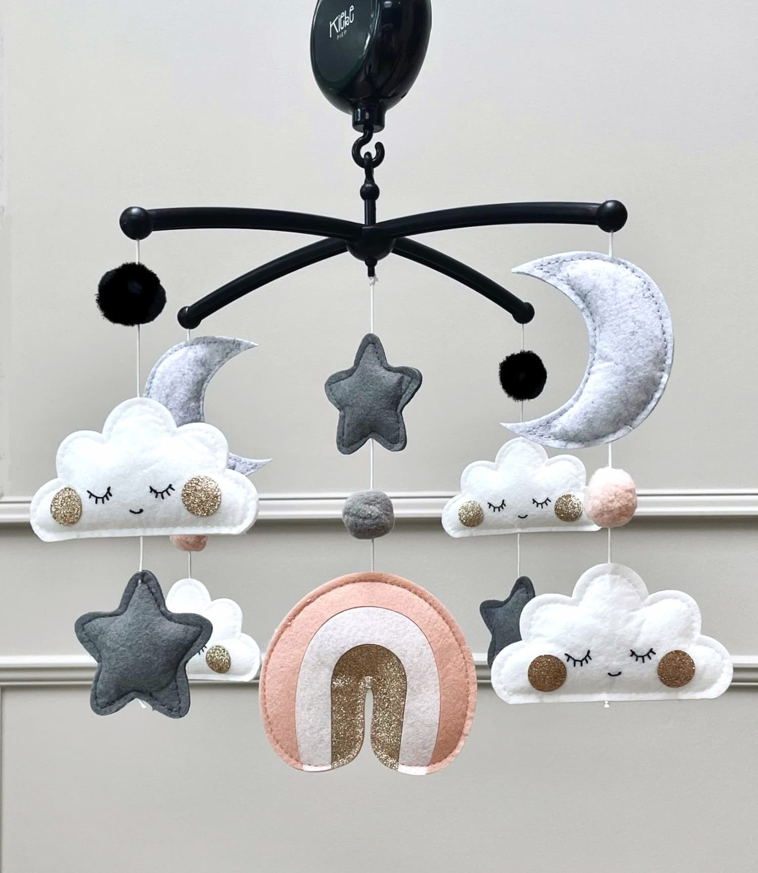 Muziekmobiel met roze regenboog van vilt – zwarte houder met wolkjes, maantjes, sterretjes en druppels van goud – handgemaakt ontwerp van Kiekepiep